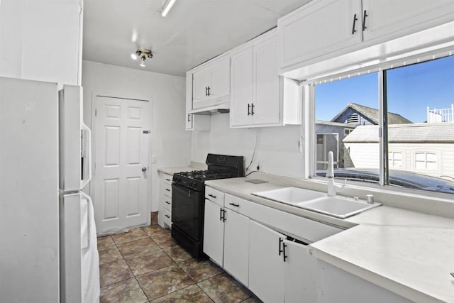 kitchen with dark tile patterned flooring, white refrigerator, sink, gas stove, and white cabinetry