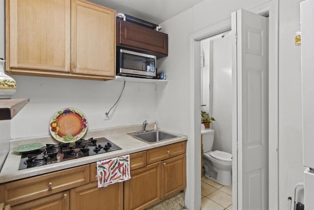 kitchen with white gas stovetop, light tile patterned floors, and sink