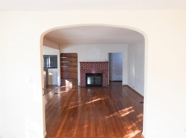 unfurnished living room featuring dark hardwood / wood-style floors and a brick fireplace