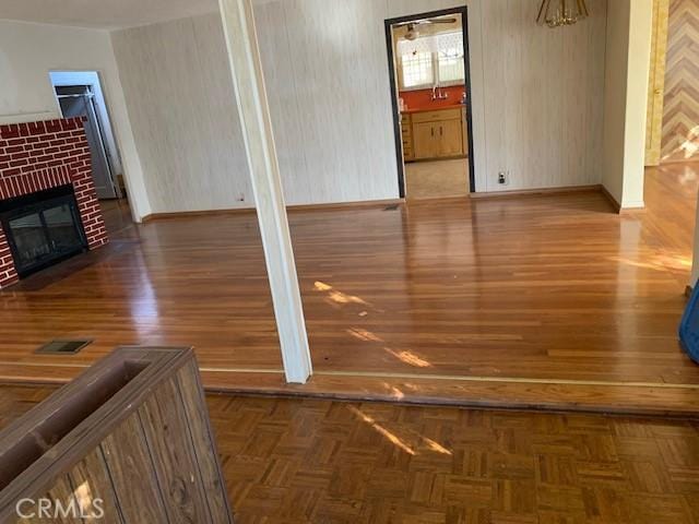 unfurnished living room featuring parquet floors, baseboards, a brick fireplace, and visible vents