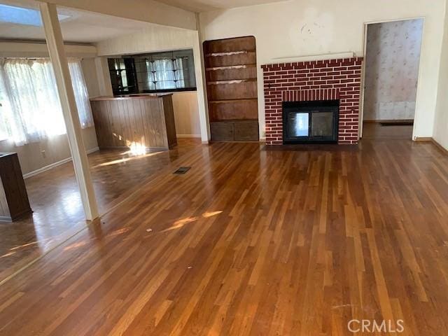 unfurnished living room with visible vents, a fireplace, baseboards, and wood finished floors