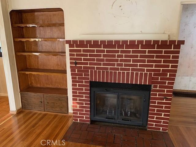 details with a brick fireplace and wood finished floors