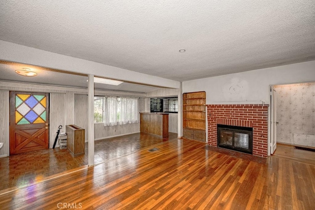 unfurnished living room featuring a fireplace, wood finished floors, and a textured ceiling