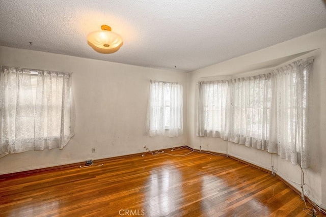 empty room with wood finished floors and a textured ceiling