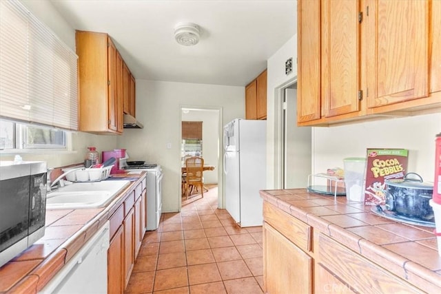 kitchen with light tile patterned floors, white appliances, tile counters, and sink