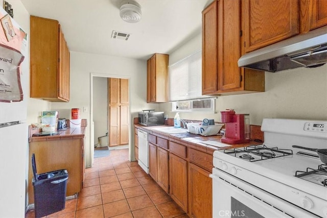 kitchen with tile countertops, light tile patterned floors, white appliances, and extractor fan