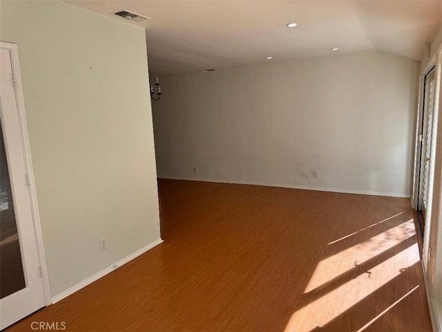 empty room featuring wood-type flooring and an inviting chandelier