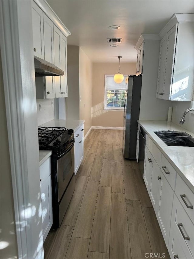 kitchen with black appliances, white cabinets, sink, light hardwood / wood-style flooring, and decorative light fixtures