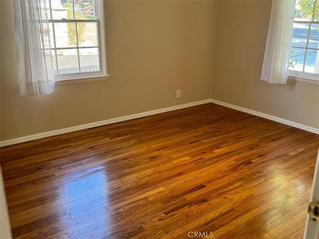 spare room with a healthy amount of sunlight and dark wood-type flooring