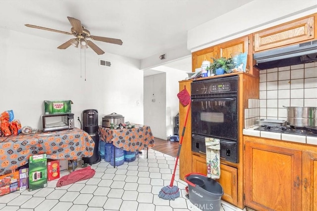 kitchen with decorative backsplash, extractor fan, ceiling fan, tile countertops, and oven