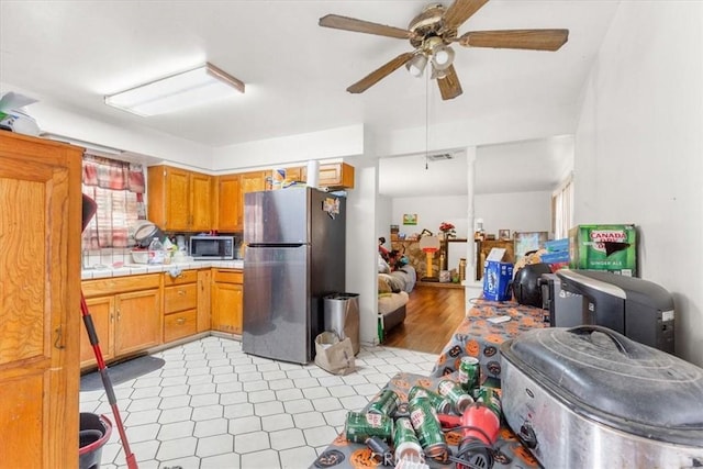 kitchen featuring stainless steel appliances, light hardwood / wood-style flooring, tile counters, and ceiling fan