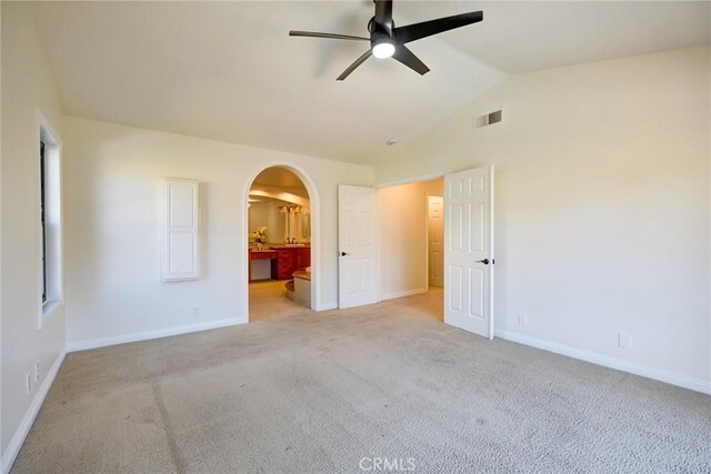 unfurnished bedroom with ensuite bath, ceiling fan, light colored carpet, and lofted ceiling