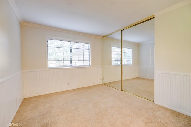 unfurnished bedroom featuring multiple windows, a closet, carpet floors, and ornamental molding