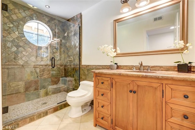 bathroom with vanity, a shower with door, tile walls, tile patterned flooring, and toilet