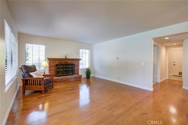 sitting room with a brick fireplace, plenty of natural light, and light hardwood / wood-style flooring