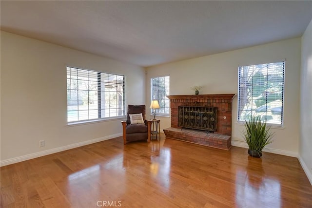 living area with a brick fireplace and hardwood / wood-style flooring