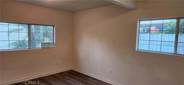 empty room featuring dark hardwood / wood-style floors, a healthy amount of sunlight, and crown molding