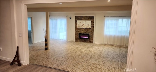 unfurnished living room with a fireplace, wood-type flooring, and plenty of natural light