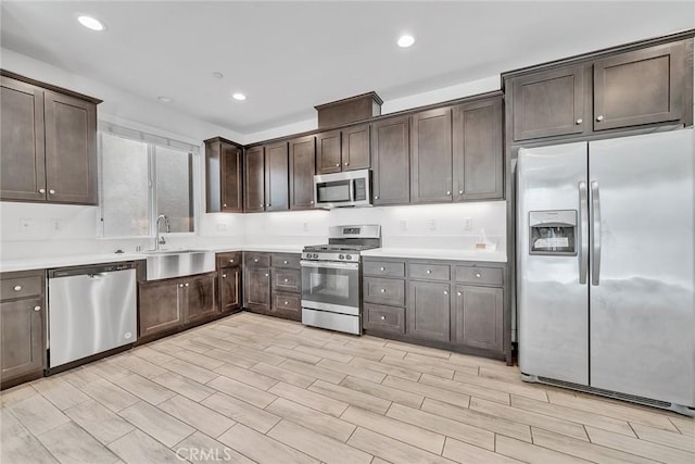 kitchen featuring appliances with stainless steel finishes, light hardwood / wood-style flooring, dark brown cabinets, and sink