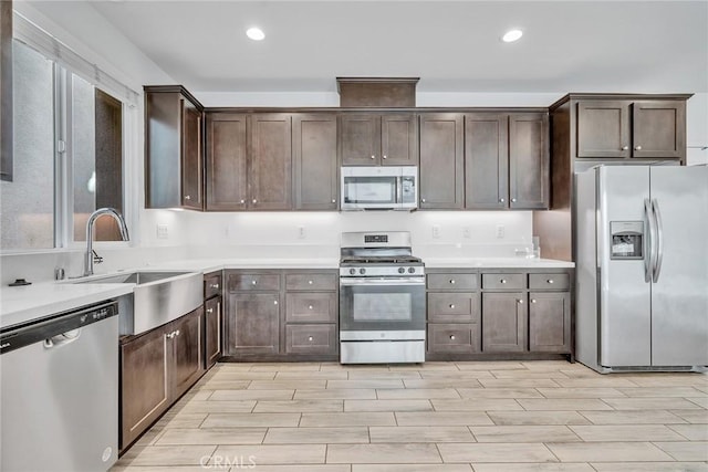 kitchen with dark brown cabinets, light wood-type flooring, sink, and appliances with stainless steel finishes