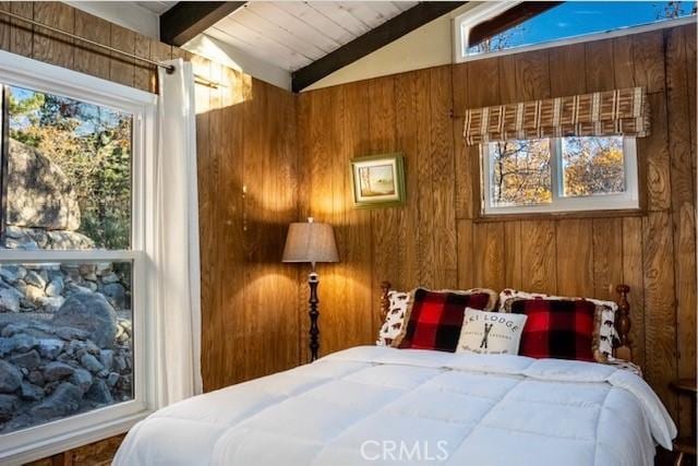 bedroom featuring vaulted ceiling with beams, wood walls, and multiple windows