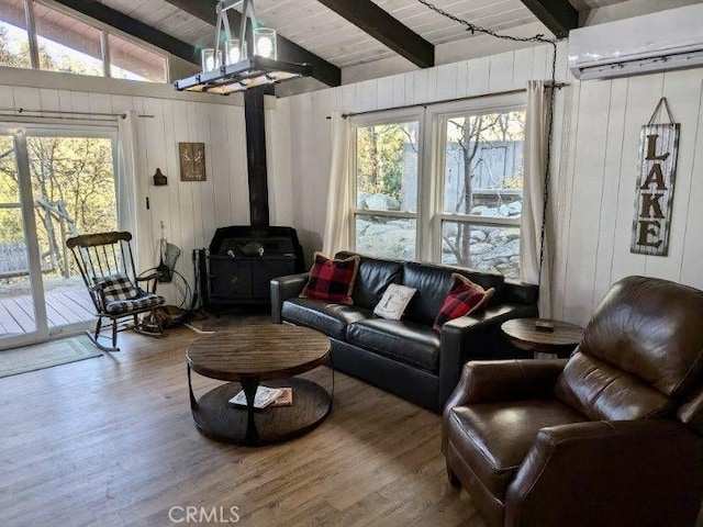 living room featuring a wall mounted AC, wood-type flooring, wooden ceiling, vaulted ceiling with beams, and a wood stove