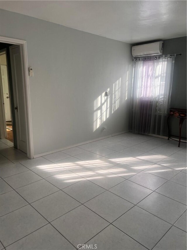 empty room with light tile patterned floors and a wall mounted air conditioner