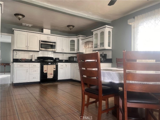 kitchen with white cabinetry, backsplash, and black range with gas cooktop