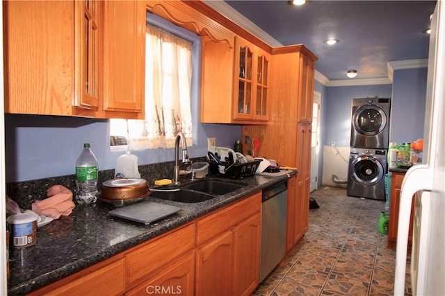 kitchen featuring sink, dark stone countertops, stainless steel dishwasher, ornamental molding, and stacked washer / dryer