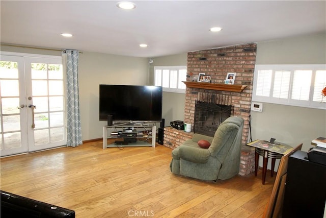 living room featuring a fireplace, light hardwood / wood-style floors, and french doors