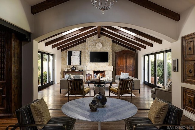 dining space featuring beam ceiling, a stone fireplace, wood-type flooring, and high vaulted ceiling