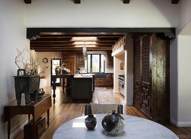 dining area with beam ceiling, dark hardwood / wood-style flooring, and sink