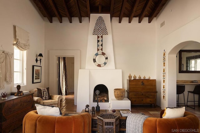 living room featuring beamed ceiling, a high ceiling, tile patterned flooring, and wooden ceiling