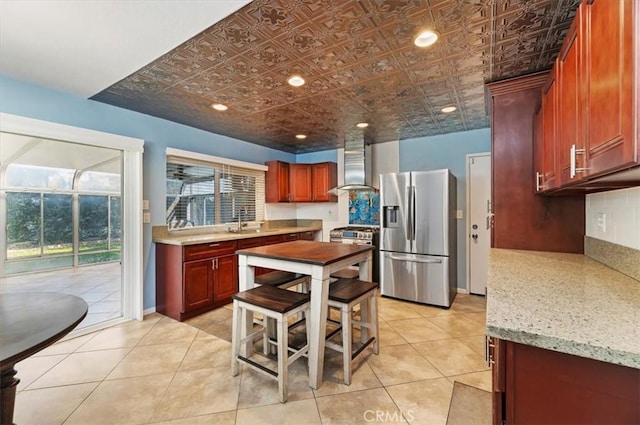 kitchen featuring wall chimney exhaust hood, light stone countertops, sink, and appliances with stainless steel finishes