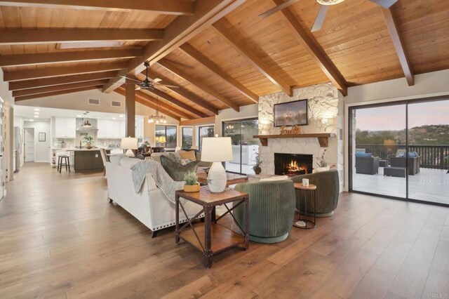 living room featuring hardwood / wood-style flooring, beam ceiling, a fireplace, and high vaulted ceiling