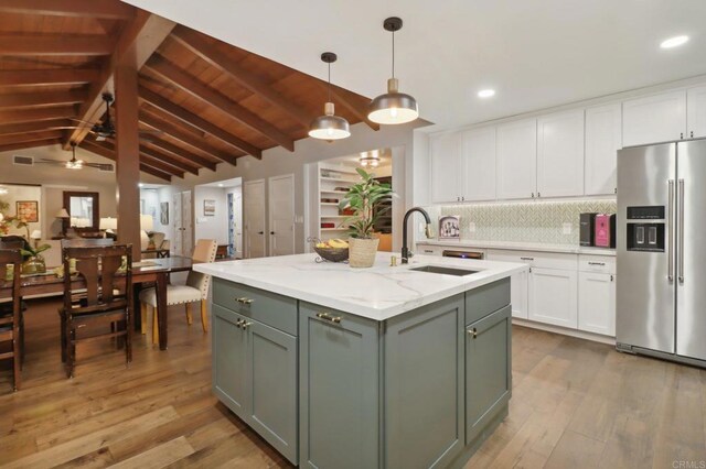 kitchen featuring hardwood / wood-style floors, lofted ceiling with beams, sink, stainless steel fridge with ice dispenser, and white cabinetry