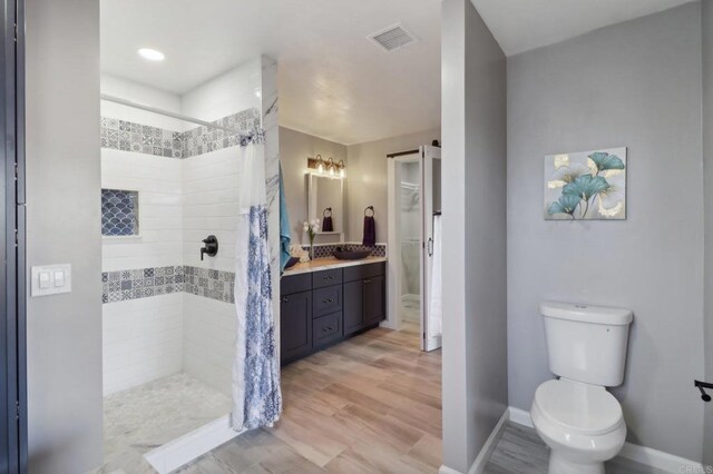 bathroom featuring vanity, hardwood / wood-style flooring, toilet, and curtained shower