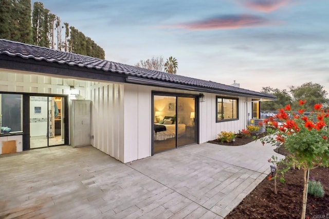 back house at dusk featuring a patio area