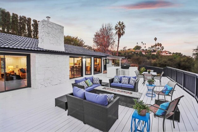 deck at dusk featuring an outdoor living space with a fire pit