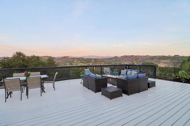 deck at dusk with outdoor lounge area and a mountain view