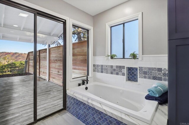 bathroom with hardwood / wood-style floors and tiled bath