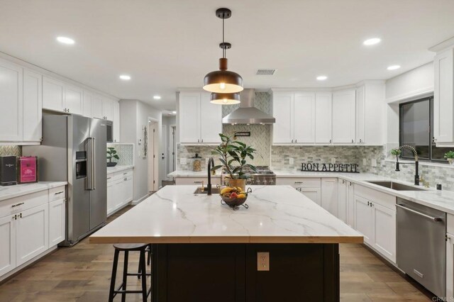 kitchen featuring wall chimney exhaust hood, stainless steel appliances, sink, a center island, and dark hardwood / wood-style floors