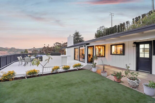 back house at dusk featuring a yard