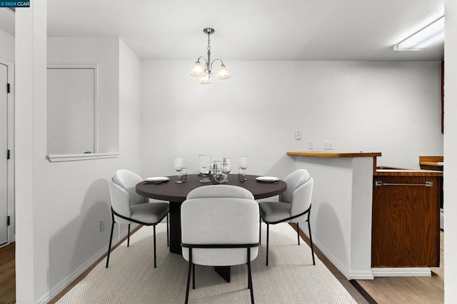 dining area with light wood-type flooring and a notable chandelier