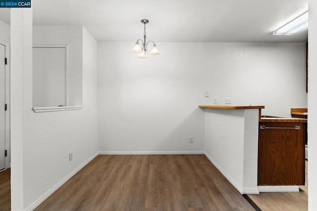 unfurnished dining area with wood-type flooring and an inviting chandelier