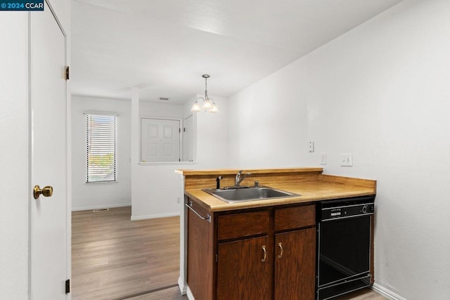 kitchen featuring sink, pendant lighting, light hardwood / wood-style flooring, a chandelier, and black dishwasher