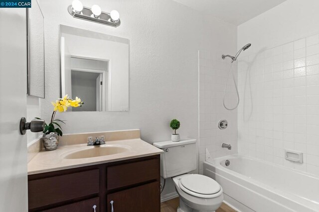 full bathroom featuring vanity, tiled shower / bath combo, and toilet