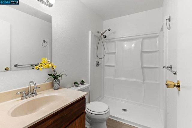 bathroom with a shower, hardwood / wood-style floors, vanity, and toilet