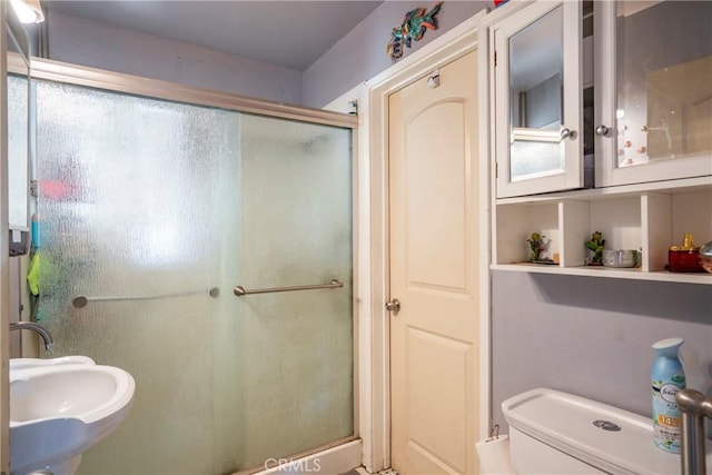 bathroom with sink, an enclosed shower, and toilet