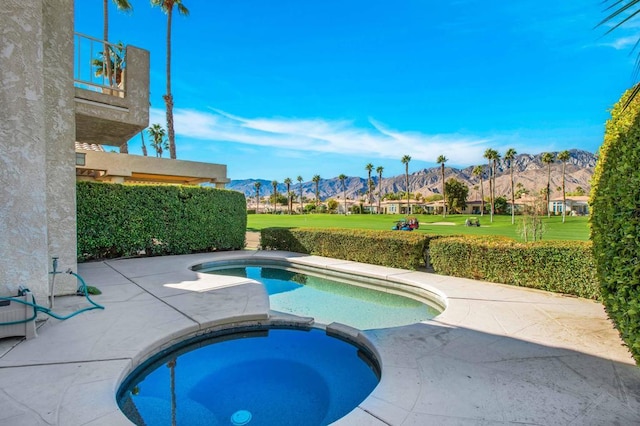 view of swimming pool with a patio area, an in ground hot tub, a yard, and a mountain view